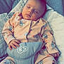 baby, sleeping, onesie, cartoon_characters, baby_seat, cushion, infant, cozy, peaceful, cute, child, soft_lighting, indoors, comfort, hands, face, head, clothing, resting, newborn