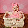 baby, bow, child, cute, decor, face, floor, flower_garland, happy, headband, indoor, infant, pink_background, pink_dress, portrait, sitting, smile, toddler, wood, wooden_drawer