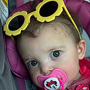 Avery is registered to the contest to win money with this photo: baby, child, pacifier, sunglasses, yellow, pink, car_seat, face, blue_eyes, clothing, cute, infant, headwear, portrait, close_up, person, seatbelt, accessory, mickey_mouse, toddler