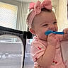 baby, child, pink_bow, headband, spoon, chewing, smiling, indoor, playpen, window_blinds, person, holding, clothing, cute, happy, infant, toddler, face, hand, room
