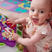 Elisa participe au concours pour gagner de l'argent avec cette photo : baby, child, smiling, toy, playing, colorful, foam_mat, indoor, happy, person, cute, head, face, clothing, furniture, pink_chair, home, floor, hands, sitting