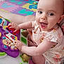 baby, child, smiling, toy, playing, colorful, foam_mat, indoor, happy, person, cute, head, face, clothing, furniture, pink_chair, home, floor, hands, sitting