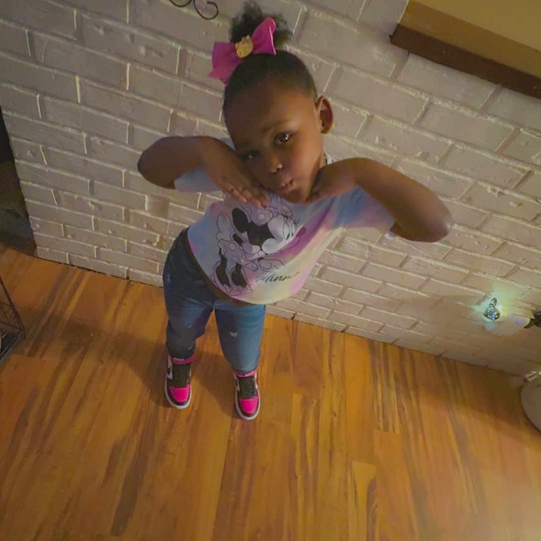 Saniyah is registered to the contest to win money with this photo: child, clothing, face, female, footwear, girl, hardwood, head, indoors, interiordesign, lighting, pants, person, photography, plywood, portrait, purple, shoe, sitting, wood