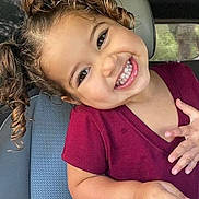 Lucciana participe au concours pour gagner de l'argent avec cette photo : toddler, child, smile, curly_hair, car_seat, maroon_shirt, happy, portrait, indoors, hand, face, person, cute, young_child, seat, vehicle_interior, expression, joy, casual_clothing, playful