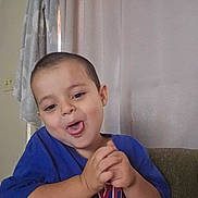 Braylen is registered to the contest to win money with this photo: blue_shirt, casual, child, clasped_hands, curtain, cute, expression, face, funny_face, hands, home, indoors, playful, portrait, sitting, smiling, toddler, tongue_out, towel, young_child