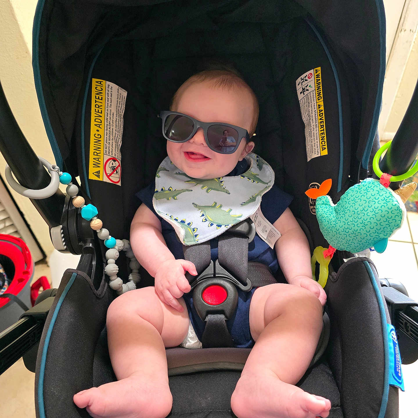 Liam is registered to the contest to win money with this photo: accessory, baby, beads, bib, car_seat, child, clothing, cute, foot, hand, happy, indoor, infant, person, portrait, reflection, seat_belt, smile, sunglasses, toy