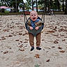 Theo is registered to the contest to win money with this photo: baby, child, infant, smiling, laughing, swing, playground, outdoor, autumn, leaves, sand, trees, park, seated, harness, bucket_swing, clothing, shoes, portrait, happy
