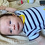 baby, infant, child, striped_clothing, onesie, blanket, bed, arm, face, head, eyes, skin, hand, fingertips, curious, lying_down, indoor, soft_texture, cute, young