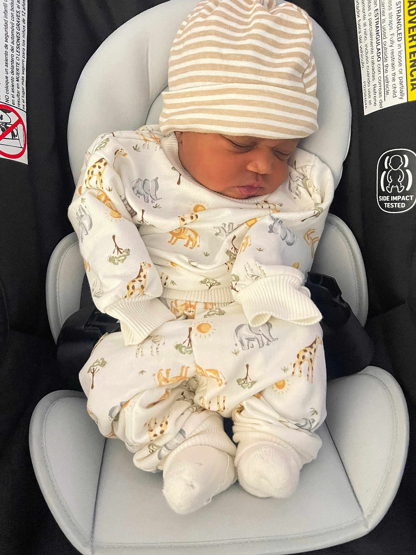 Adriel is registered to the contest to win money with this photo: baby, sleeping, car_seat, infant, hat, striped_hat, animal_print, onesie, cozy, newborn, white_clothing, cute, child, footwear, socks, seat_belt, safety, resting, indoor, portrait