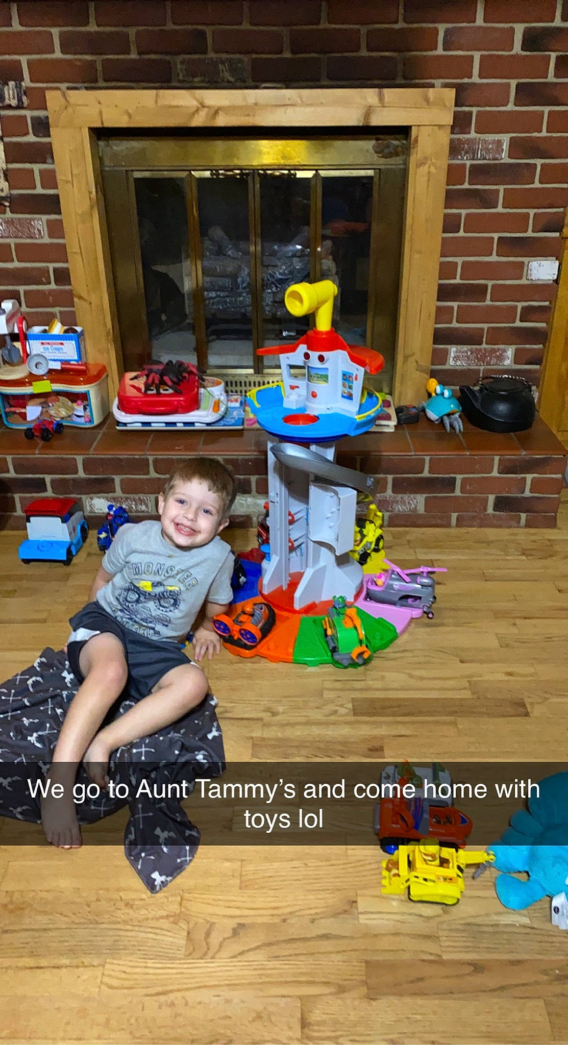 Coltyn is registered to the contest to win money with this photo: child, fictional_character, floor, flooring, fun, happy, hardwood, joy, leisure, person, play, room, shorts, sitting, smile, t_shirt, toddler, toy, toy_vehicle, wood