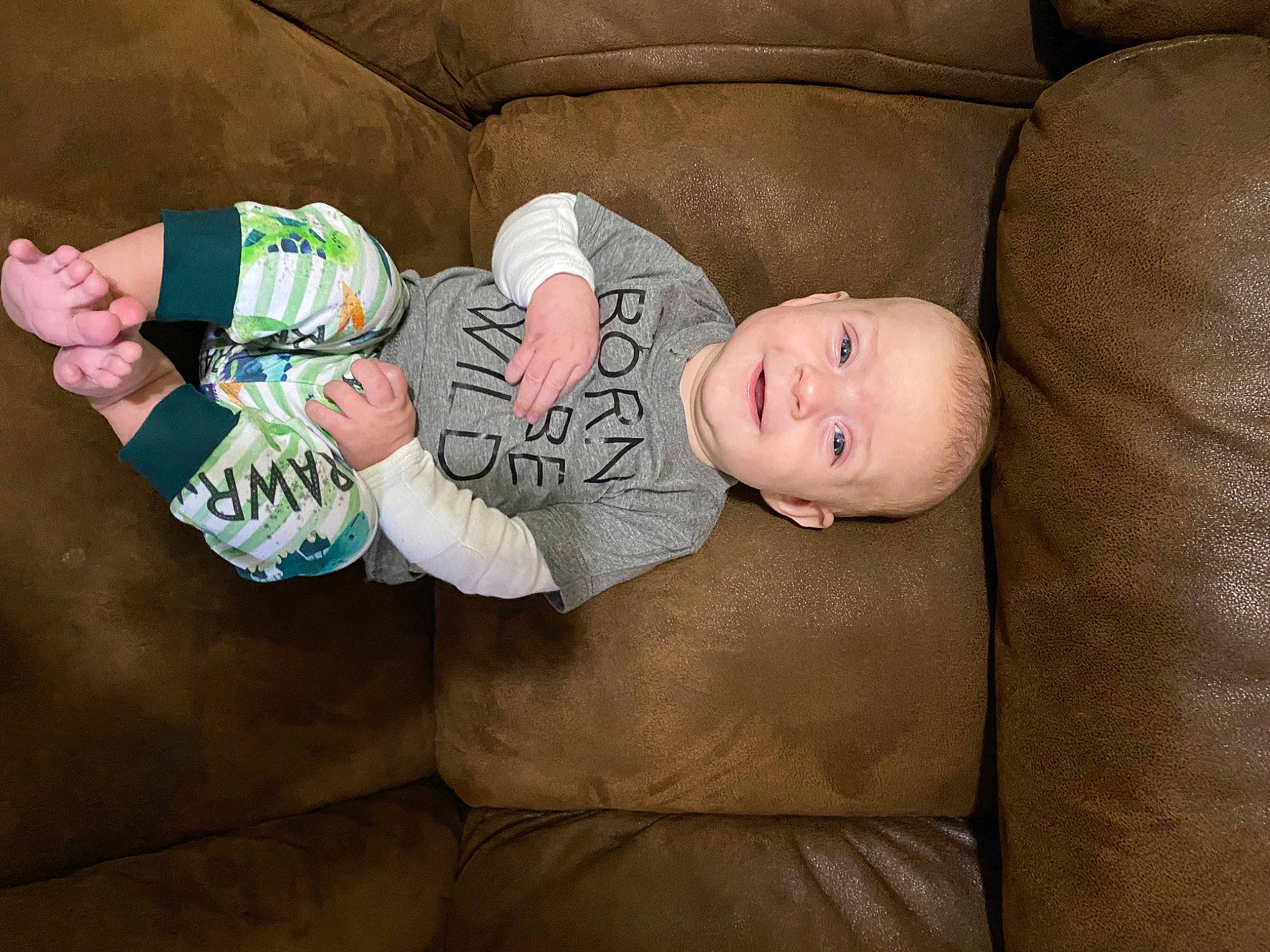 Brogan is registered to the contest to win money with this photo: baby, baby_products, baby_toddler_clothing, cheek, comfort, couch, eye, face, hand, head, human_body, leg, linens, person, room, sitting, skin, sleeve, sock, toddler