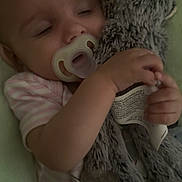 Alani is registered to the contest to win money with this photo: baby, pacifier, sleeping, stuffed_animal, monkey, soft_toy, blanket, infant, child, cute, cozy, clothing, rest, comfort, indoor, portrait, hand, face, toddler, bedtime