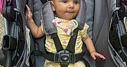 Alani is registered to the contest to win money with this photo: baby, child, stroller, car_seat, infant, yellow_clothing, pacifier, pacifier_clip, seatbelt, cute, person, sitting, outdoor, fabric, straps, head, legs, arms, expression, comfort