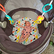 Alexis is registered to the contest to win money with this photo: baby, bright, carpet, child, clothing, colorful, comfort, cute, hanging_toy, indoor, infant, patterned_mat, person, playpen, playtime, relaxing, resting, small, soft, toy