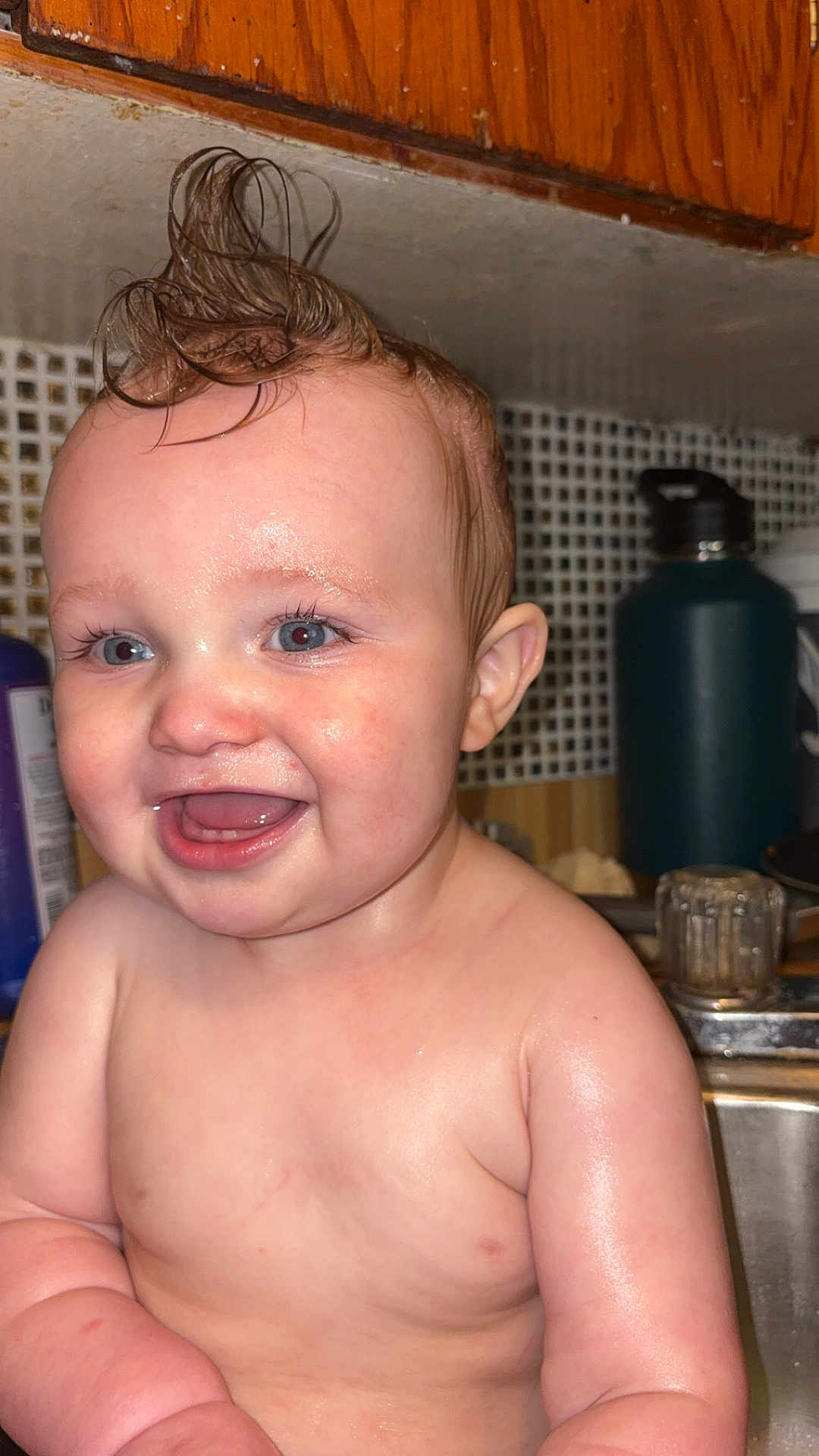 Cody is registered to the contest to win money with this photo: baby, child, wet_hair, mohawk, smile, kitchen, sink, blue_eyes, skin, arm, face, happy, indoors, water, person, expression, cute, chubby, closeup, funny_hairstyle