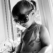 Ava joined the competition — help win amazing prizes! child, girl, sunglasses, window, tulips, flower, sunlight, black_and_white, dress, toy, handheld_device, portrait, indoors, cute, person, young_child, hair, pigtails, reflection, natural_light
