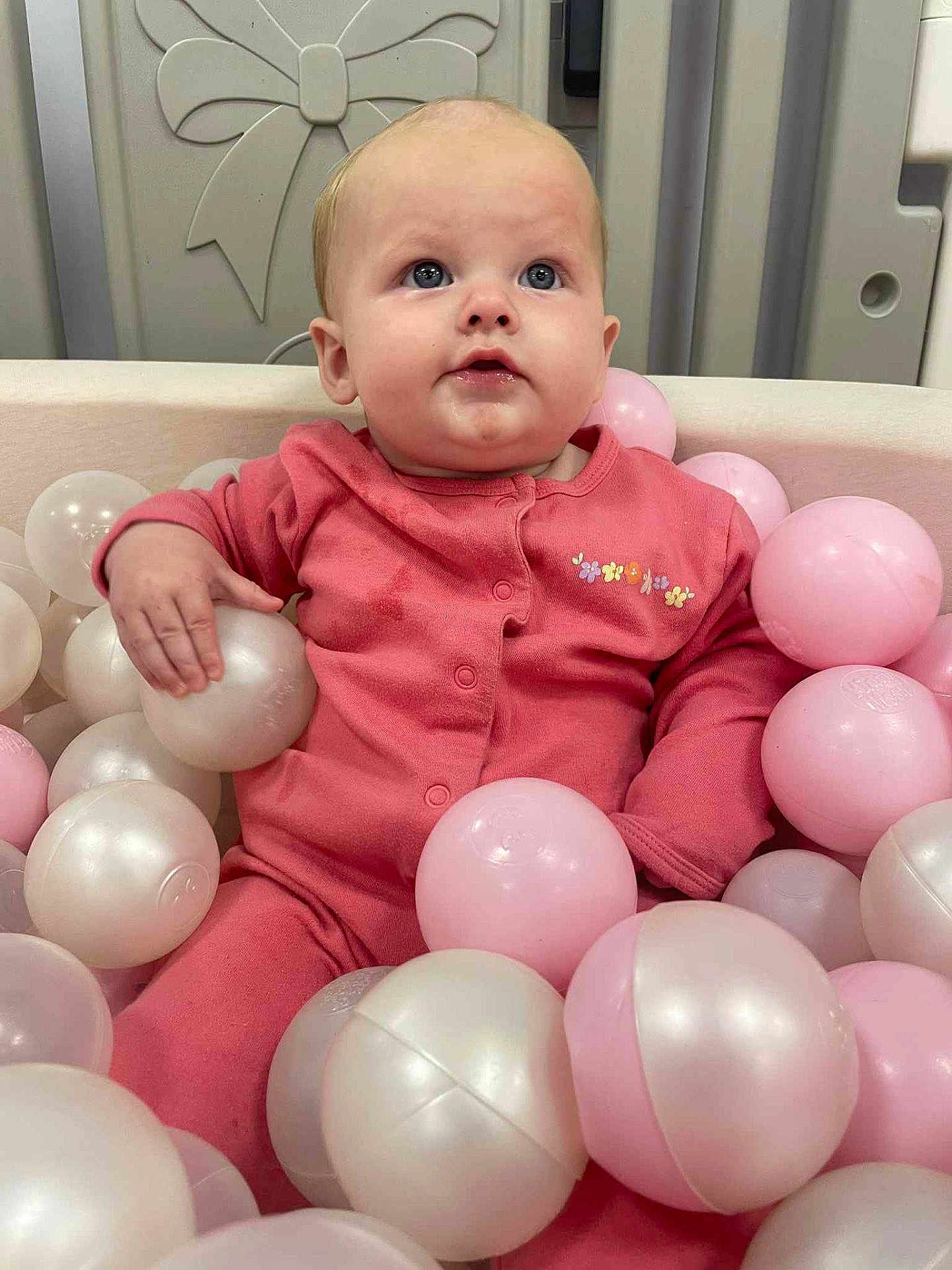 Elsie joined the competition — help win amazing prizes! baby, child, pink_outfit, ball_pit, plastic_balls, indoor, cute, portrait, infant, playtime, soft_toys, happy, childhood, smiling, face, hand, seated, looking_up, cozy, adorable