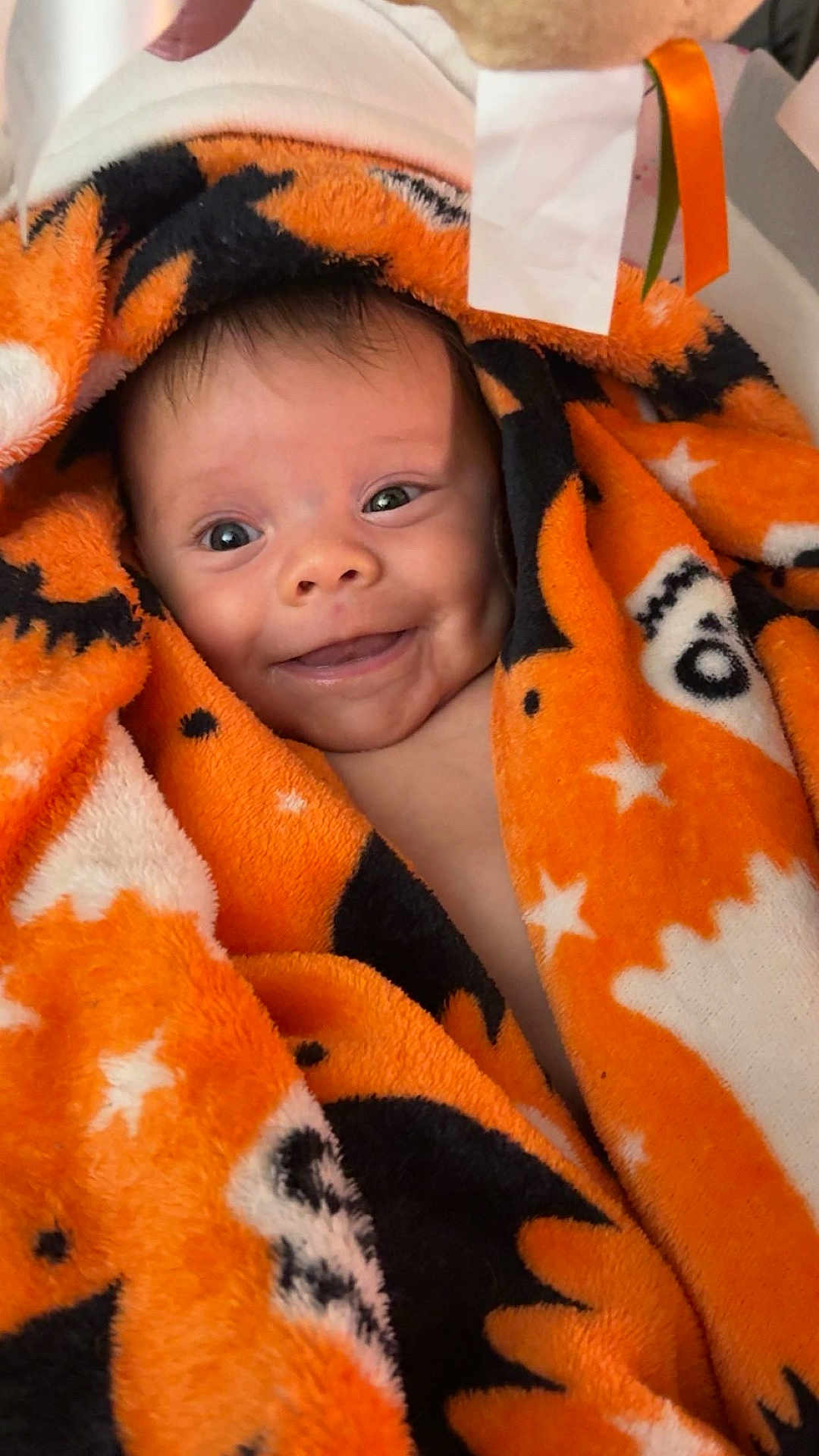 Anya Elaine Pulciani is registered to the contest to win money with this photo: baby, black, blanket, child, closeup, cozy, cute, expression, face, happy, indoors, infant, orange, portrait, smiling, soft, stars, warm, wrapped, young
