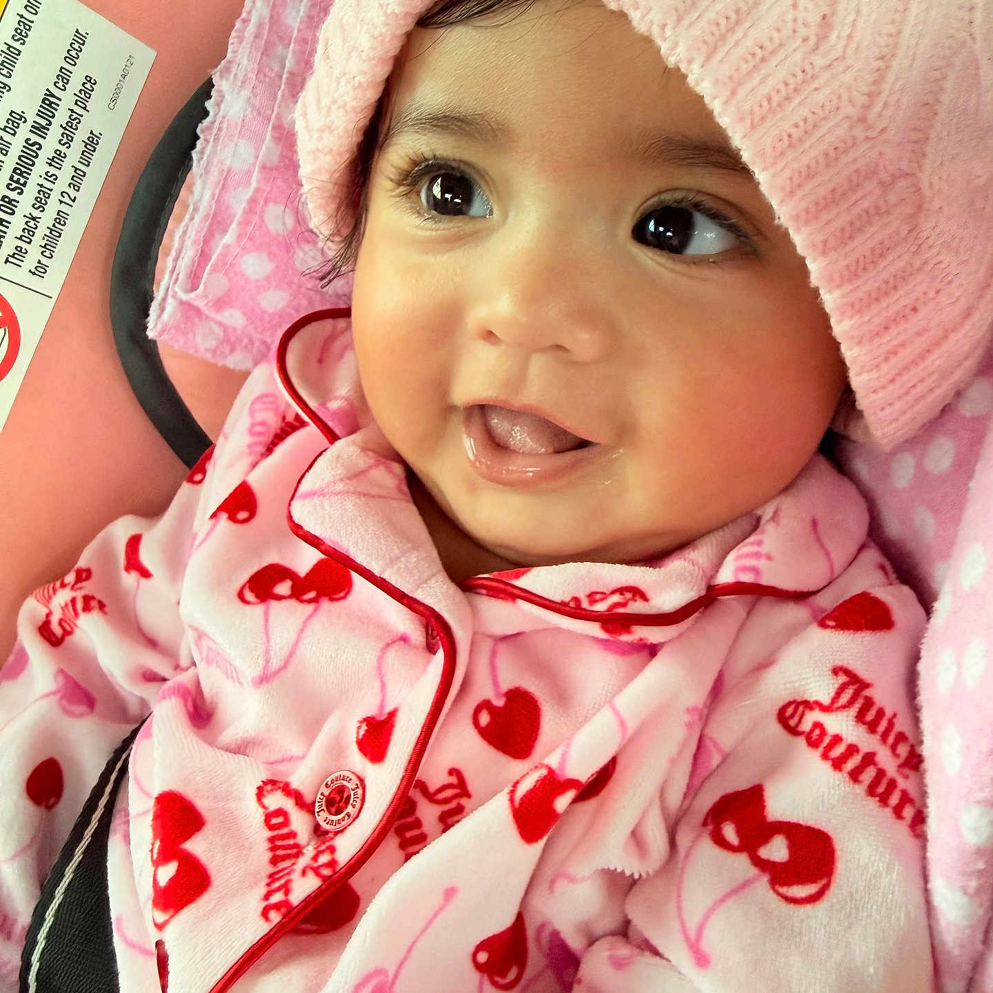 Jaynara Rodas is registered to the contest to win money with this photo: baby, infant, child, portrait, smiling, tongue_out, pink, hat, knit_hat, onesie, cherry_pattern, heart_pattern, car_seat, seatbelt, close_up, indoor, happy, face, blanket, photography