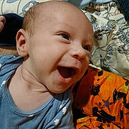 Caleb joined the competition — help win amazing prizes! baby, smiling, blue_onesie, stars_pattern, blanket, orange_blanket, halloween_pattern, happy, infant, face, head, person, closeup, indoors, cute, child, skin, expression, joy, clothing
