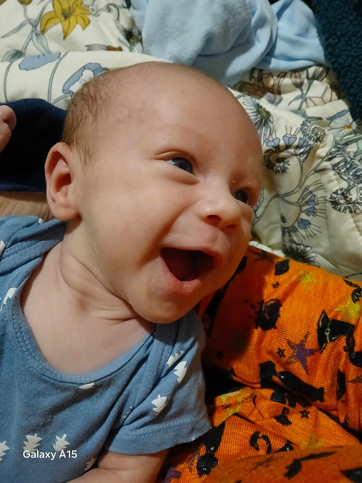 Caleb joined the competition — help win amazing prizes! baby, smiling, blue_onesie, stars_pattern, blanket, orange_blanket, halloween_pattern, happy, infant, face, head, person, closeup, indoors, cute, child, skin, expression, joy, clothing