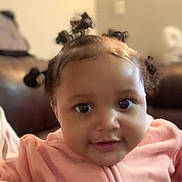 Mahogany joined the competition — help win amazing prizes! baby, child, indoor, portrait, pink_clothing, cute, hair_buns, smile, face, eyes, infant, young_child, couch, cozy, closeup, person, adorable, soft_lighting, expression, sitting
