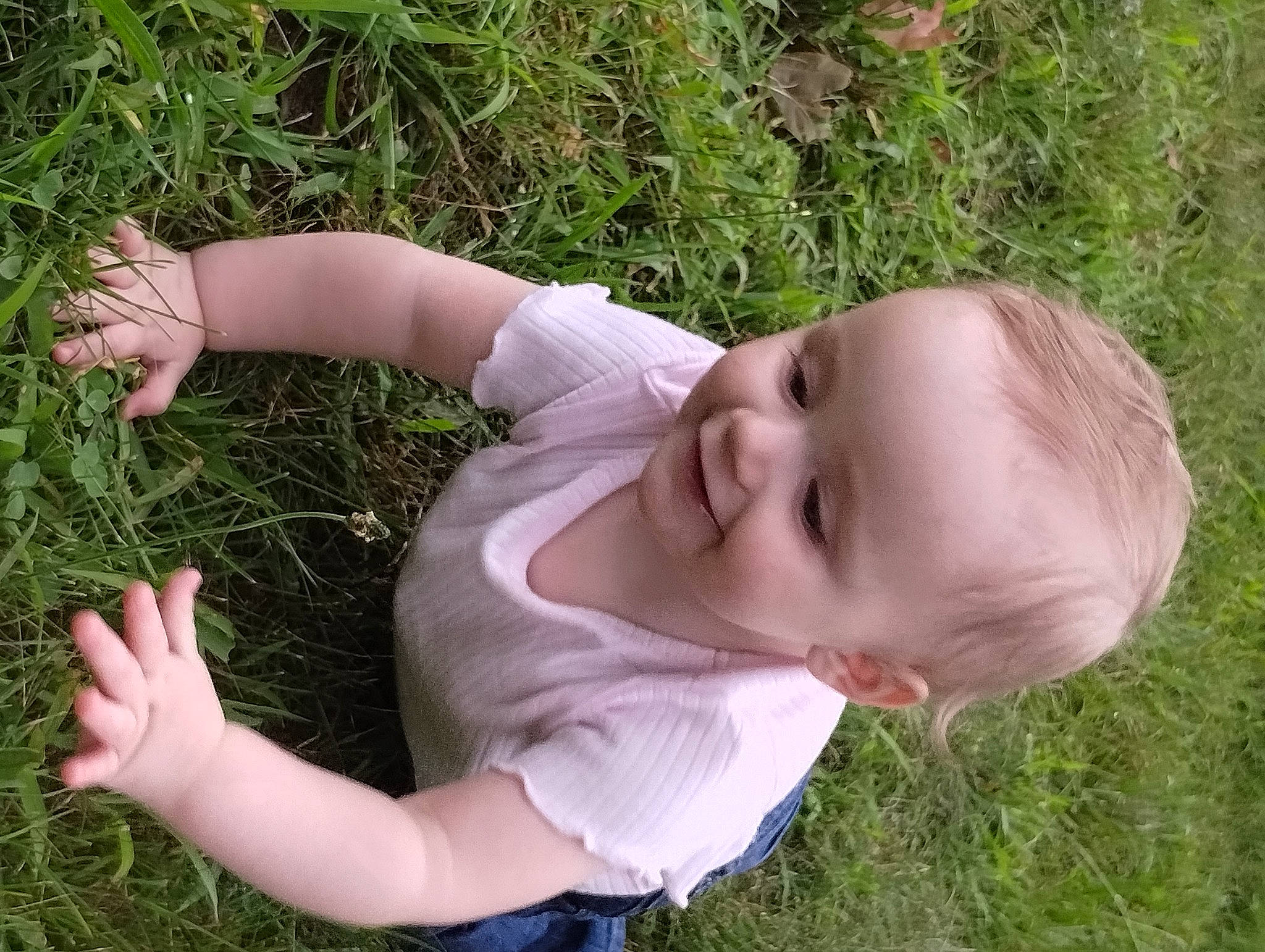 Octavia is registered to the contest to win money with this photo: baby, baby_toddler_clothing, child, facial_expression, finger, fun, grass, grass_family, grassland, hand, happy, joy, lawn, meadow, people_in_nature, person, plant, skin, smile, thumb