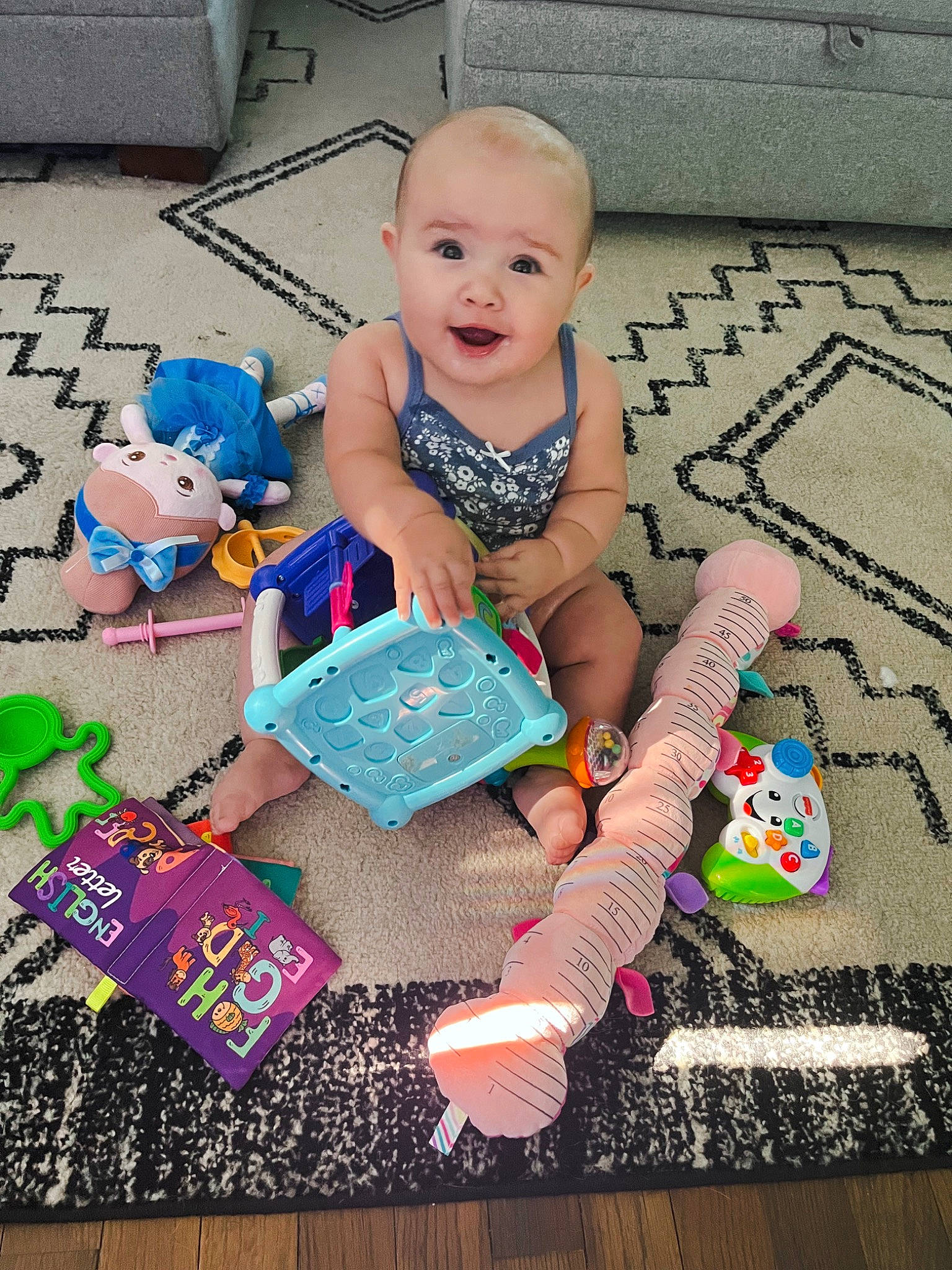 Addison joined the competition — help win amazing prizes! baby, baby_toddler_clothing, child, doll, flooring, fun, happy, lap, linens, pattern, person, pink, play, room, sitting, smile, sock, t_shirt, textile, toddler