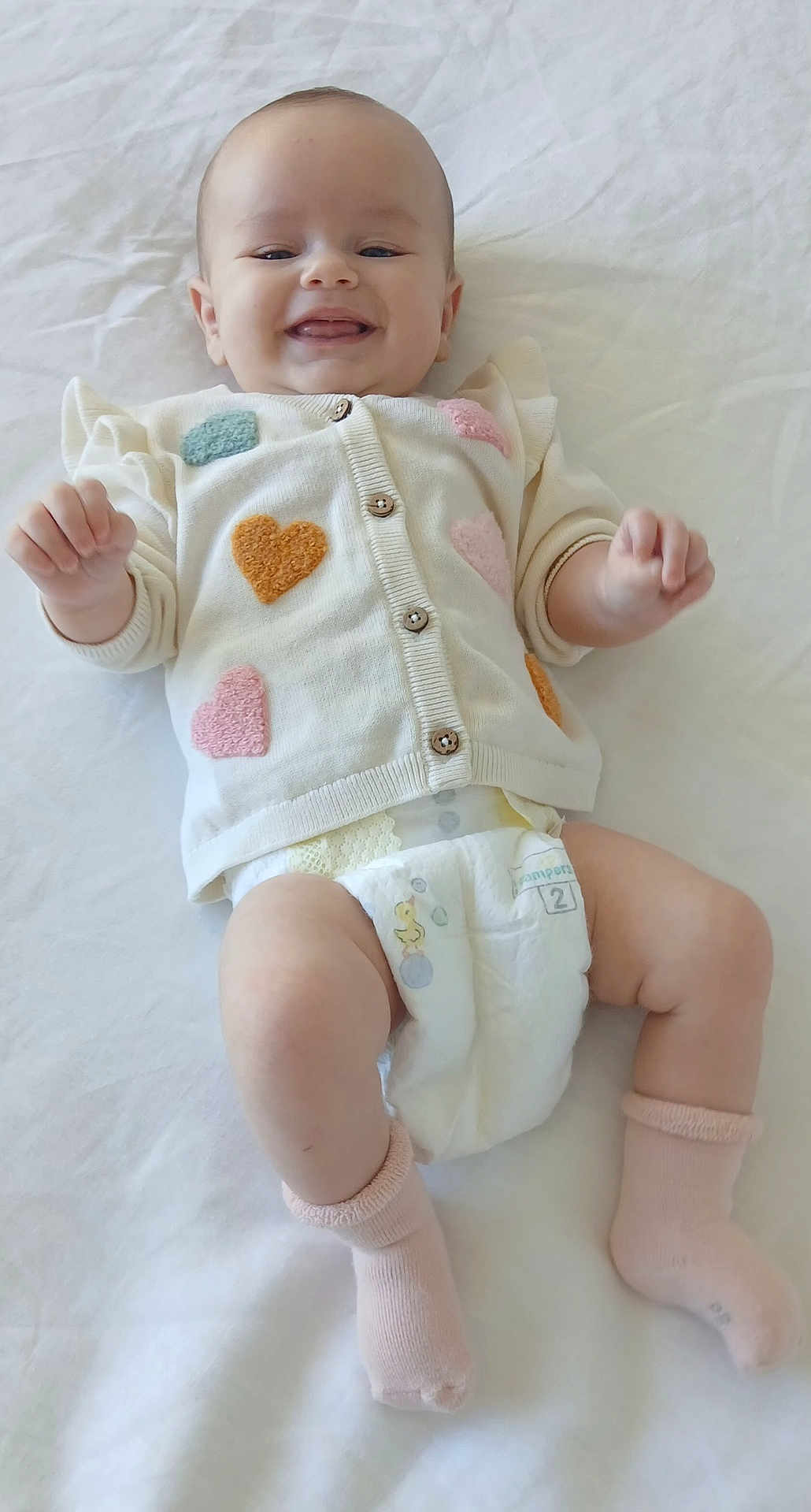 Olyvia a rejoint le concours — aidez-le/la à gagner de superbes lots ! baby, child, smiling, cardigan, hearts, diaper, pink_socks, lying_down, white_background, infant, cute, happy, soft_texture, close_up, portrait, person, indoors, clothing, baby_garment, toddler