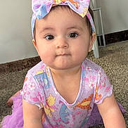 Aria is registered to the contest to win money with this photo: baby, child, infant, headband, bow, purple_clothing, cartoon_characters, carpet, indoor, cute, face, eyes, smile, person, toddler, apparel, fashion, sitting, young, playful