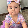 baby, child, infant, headband, bow, purple_clothing, cartoon_characters, carpet, indoor, cute, face, eyes, smile, person, toddler, apparel, fashion, sitting, young, playful