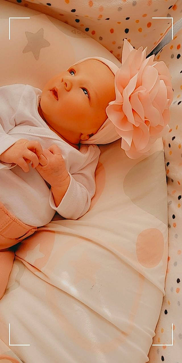 Gabriella a rejoint le concours — aidez-le/la à gagner de superbes lots ! baby, baby_sleeping, baby_toddler_clothing, bedding, child, comfort, fashion_accessory, finger, flower, happy, headwear, linens, orange, peach, person, petal, pink, skin, sweetness, textile