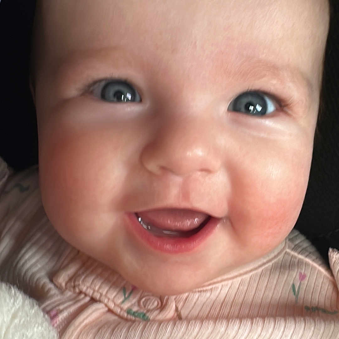 Maggie joined the competition — help win amazing prizes! baby, blanket, blue_eyes, cheeks, child, close_up, cute, expression, face, happy, head, infant, mouth, pink_clothing, portrait, skin, smiling, soft_texture, tongue, young