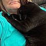 black_cat, cat, chin, close_up, comfort, couch, cuddling, fur, glasses, indoor, paw, person, pet, portrait, resting, senior_person, sleeping_cat, teal_shirt, texture, whiskers