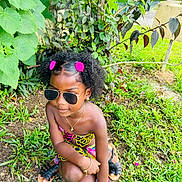 Jayna participe au concours pour gagner de l'argent avec cette photo : accessories, backyard, blackhair, child, clothing, curlyhair, face, female, footwear, girl, hair, head, nature, outdoors, person, photography, portrait, sitting, sunglasses, yard