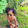 accessories, backyard, blackhair, child, clothing, curlyhair, face, female, footwear, girl, hair, head, nature, outdoors, person, photography, portrait, sitting, sunglasses, yard