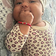 Celeste is registered to the contest to win money with this photo: baby, infant, child, portrait, lying_down, smiling, face, eyes, hand, fist, leopard_print, outfit, headwrap, turban, bracelet, blanket, cozy, indoors, close_up, cute