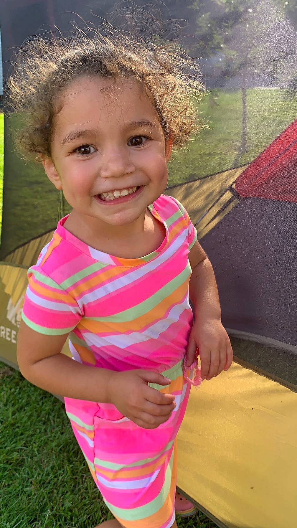 Kiara is registered to the contest to win money with this photo: eye, face, facial_expression, fun, grass, hairstyle, happy, head, human_body, joy, leaf, leisure, lip, people_in_nature, person, pink, plant, skin, smile, tent