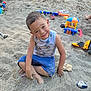 child, boy, sand, outdoor, play, toys, smile, happy, barefoot, shorts, tank_top, dirt, playground, summer, fun, casual_clothing, sitting, messy, daylight, nature