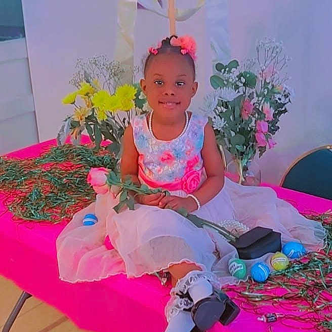 Elizabeth is registered to the contest to win money with this photo: child, clothing, face, female, flower, flowerarrangement, formalwear, furniture, girl, happy, head, people, person, photography, plant, portrait, pottedplant, sitting, smile, suit