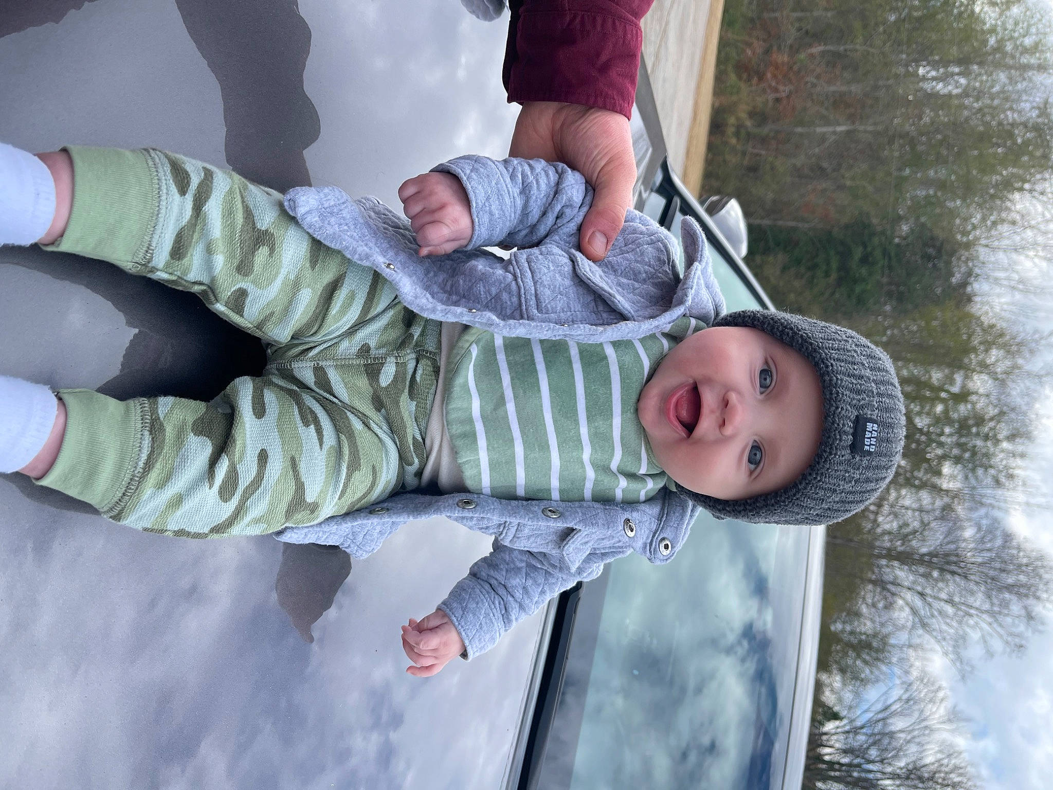 Kohen is registered to the contest to win money with this photo: baby, baby_toddler_clothing, child, clothing, comfort, freezing, fun, gesture, happy, headwear, leisure, pattern, people_in_nature, person, sky, sleeve, smile, snow, toddler, tree