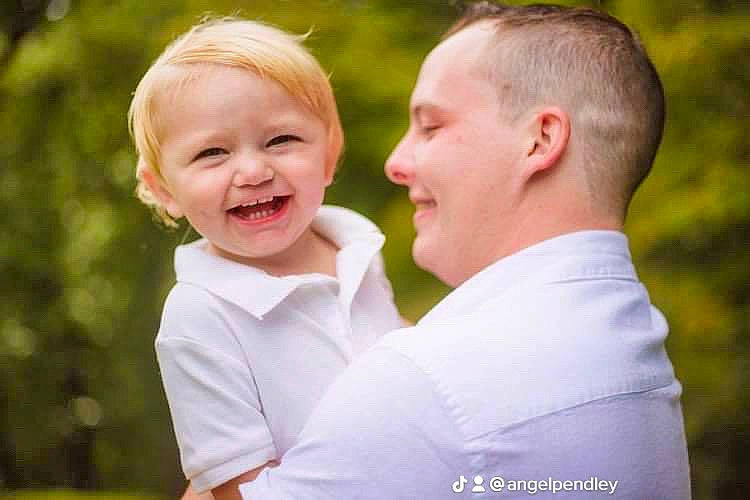 Colton is registered to the contest to win money with this photo: ceremony, child, event, facial_expression, formal_wear, fun, gesture, grass, happy, joy, laugh, love, people_in_nature, person, portrait_photography, sleeve, smile, toddler