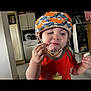 Hollyster participe au concours pour gagner de l'argent avec cette photo : toddler, child, helmet, orange_shirt, indoor, kitchen, snack, food, face, curious, young_child, person, home, cabinet, appliance, floor, hand, expression, casual, headwear