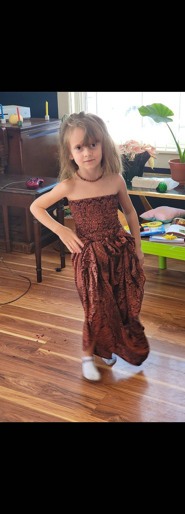 Gwendolyn is registered to the contest to win money with this photo: day_dress, fashion_design, fawn, floor, flooring, happy, hardwood, human_leg, laminate_flooring, leg, one_piece_garment, person, sleeve, smile, thigh, toddler, trunk, varnish, waist, wood