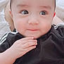 baby, infant, child, face, hand, black_clothing, curious, portrait, indoors, person, skin, cute, young, expression, resting, sitting, closeup, head, eyebrows, eyes