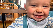 Malo a rejoint le concours — aidez-le/la à gagner de superbes lots ! toddler, child, smiling, face, overalls, striped_clothing, indoors, home, baby, happy, person, portrait, baby_bib, furniture, table, wooden_rail, window, daylight, floor, candid