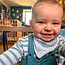 toddler, child, smiling, face, overalls, striped_clothing, indoors, home, baby, happy, person, portrait, baby_bib, furniture, table, wooden_rail, window, daylight, floor, candid