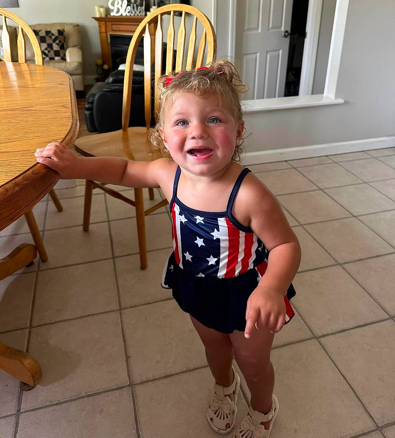 Italia is registered to the contest to win money with this photo: baby_toddler_clothing, chair, chest, floor, flooring, foot, happy, hardwood, human_leg, joint, joy, person, shoulder, sitting, sleeve, smile, table, thigh, toddler, trunk