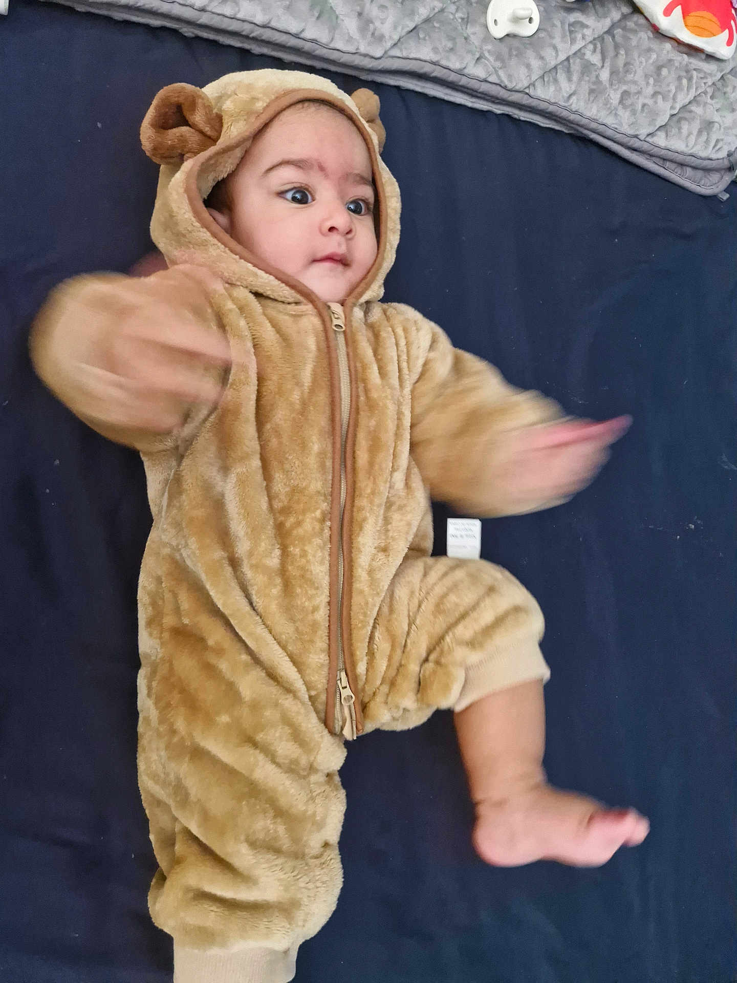 Shahzain joined the competition — help win amazing prizes! baby, child, onesie, bear_costume, fuzzy, cute, infant, motion_blur, arms, leg, pacifier, toy, blanket, soft, indoor, portrait, expression, cuteness, hood, zipped