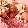 baby, infant, headband, pink, blanket, soft_texture, clothing, portrait, face, cute, sleepwear, newborn, toddler, lying_down, closeup, indoors, child, person, cozy, resting